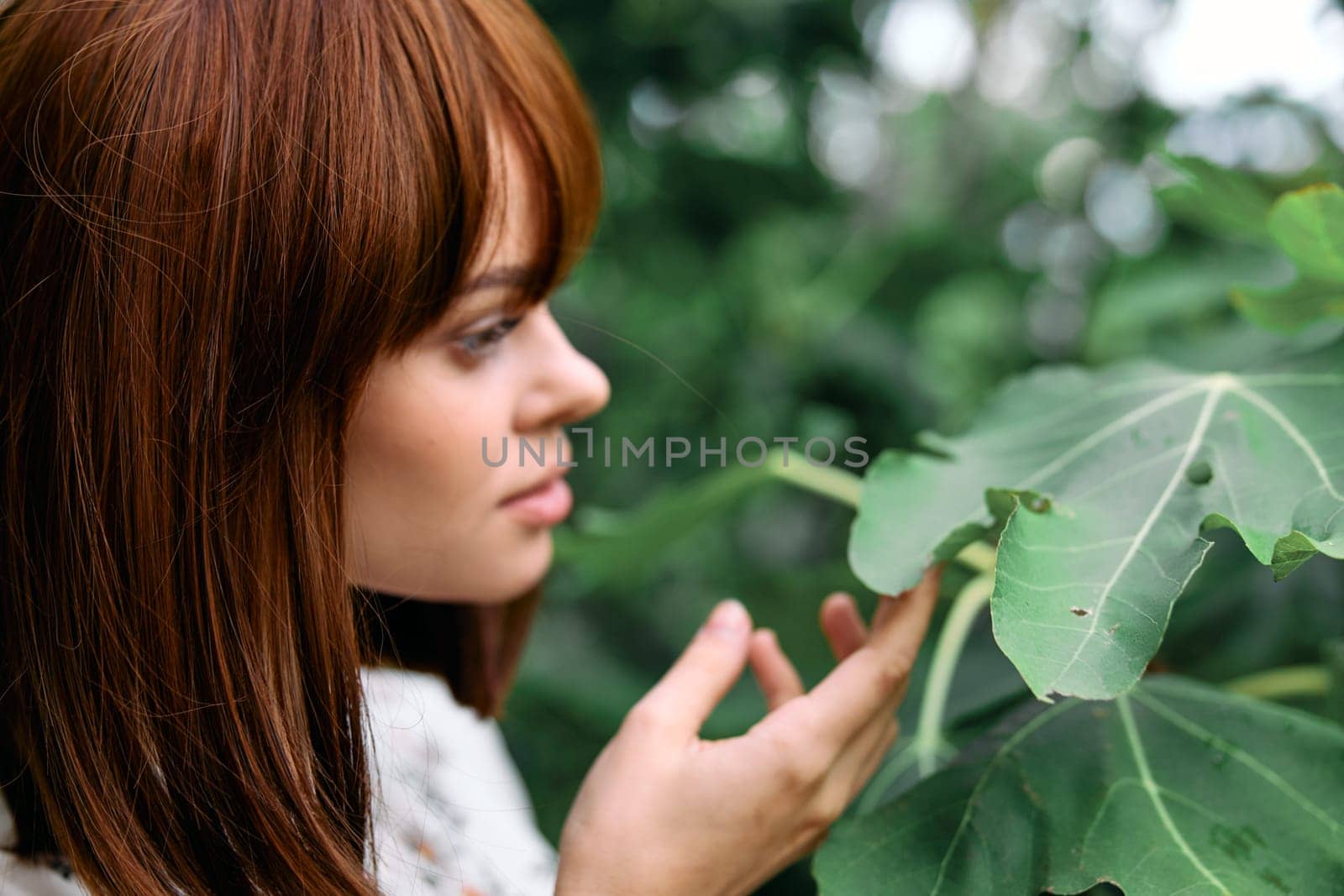 Woman with red hair admiring lush green foliage in a garden setting