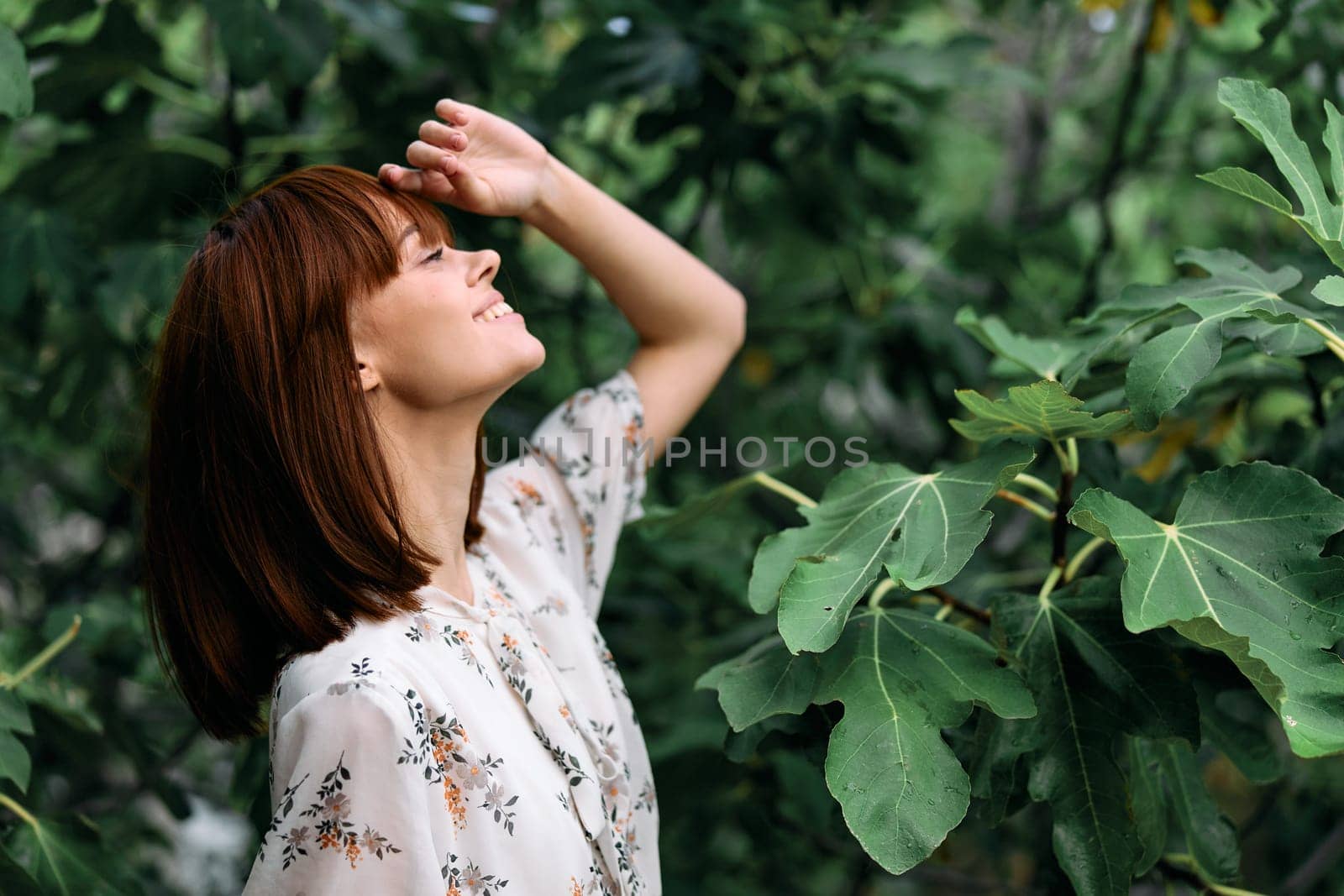 Mysterious woman standing in awe beneath tall tree with hands on head