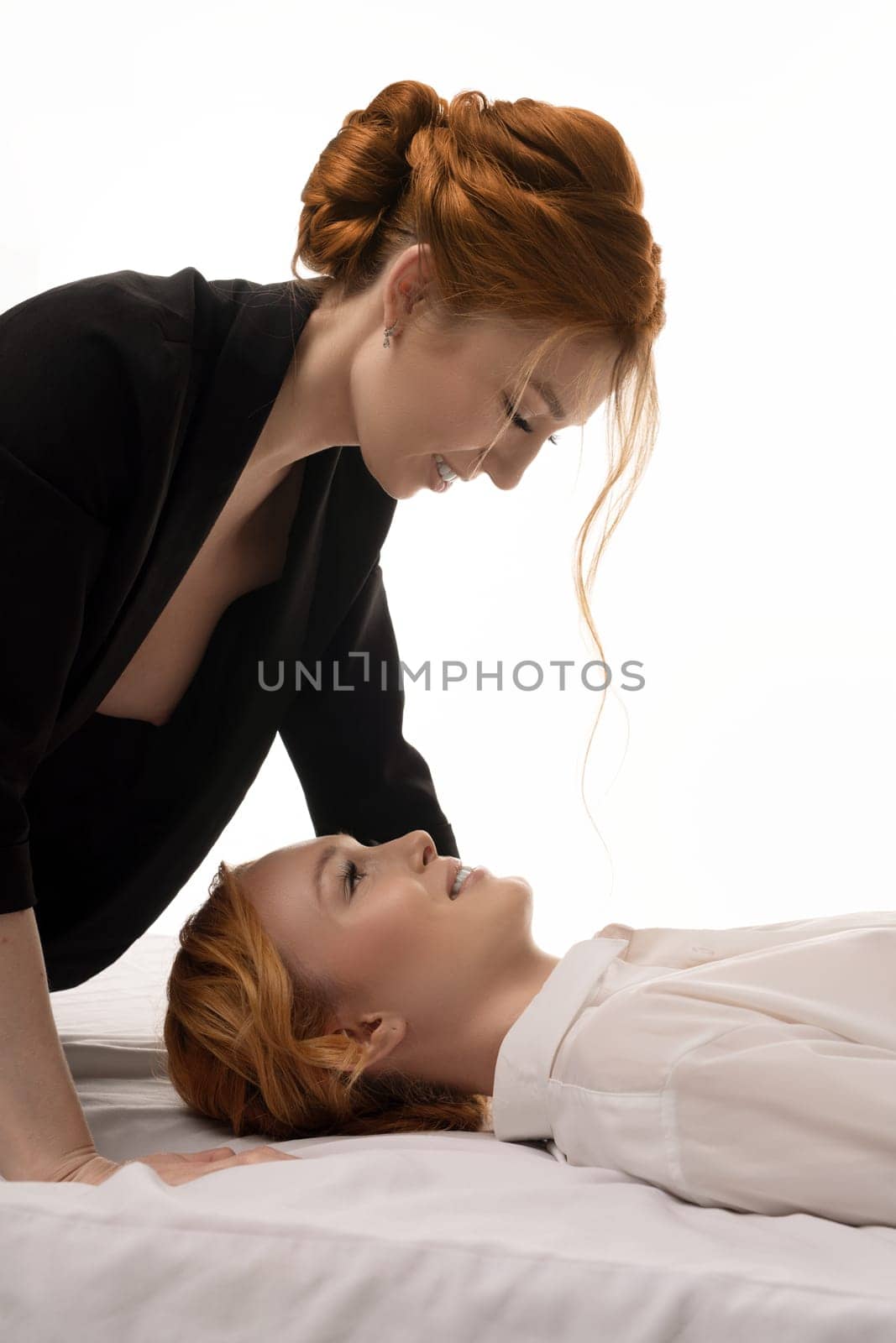naked business - Stylish young red head businesswomen lying in bed one above other in topless black suit and white shirt