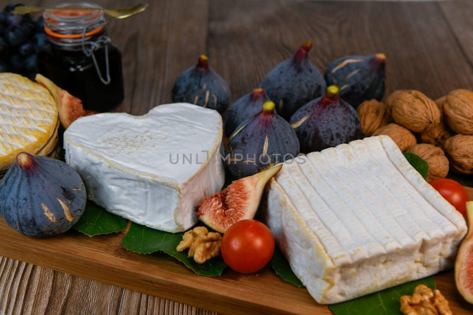 Selection of French cheeses from Normandy, AOP, Livarot, Neufchatel, Pont l'eveque, Rye bread, figs, walnuts, grapes, elderberry gelee. High quality photo