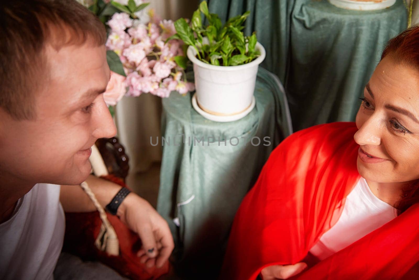 A middle-aged couple dressed in vibrant oriental attire share joyful moments while engaging in playful role-playing at home.
