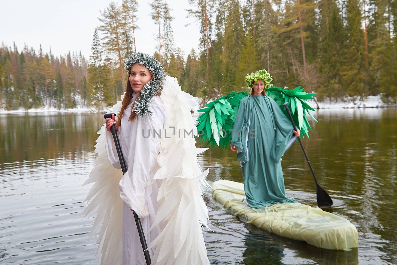 Girls dressed in white and green grace the lake, capturing the magical transition between winter and spring in their whimsical role-playing.