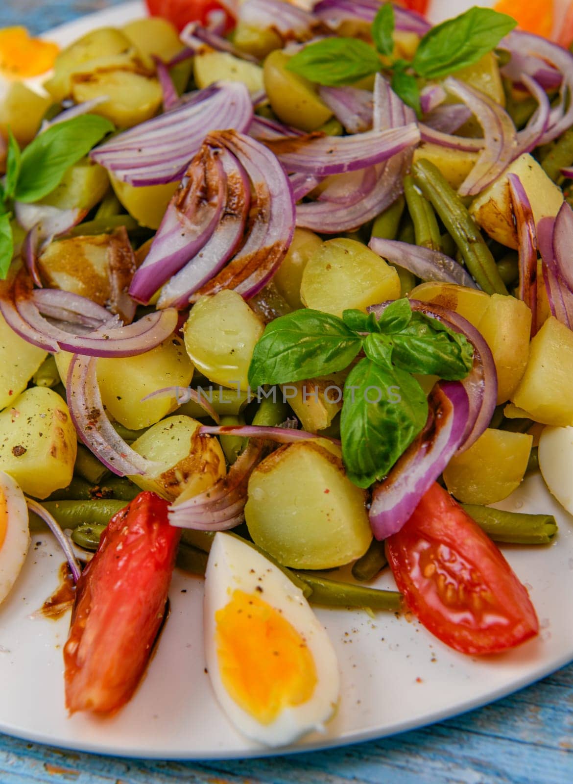 Fresh salad, green beans, small potatoes, egg, tomato, basil, red onions and balsamic vinaigrette. High quality photo