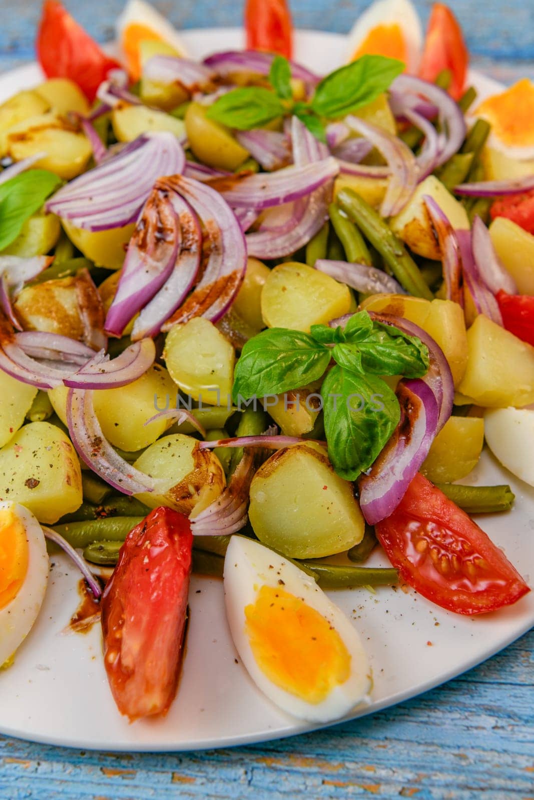 Fresh salad, green beans, small potatoes, egg, tomato, basil, red onions and balsamic vinaigrette. High quality photo