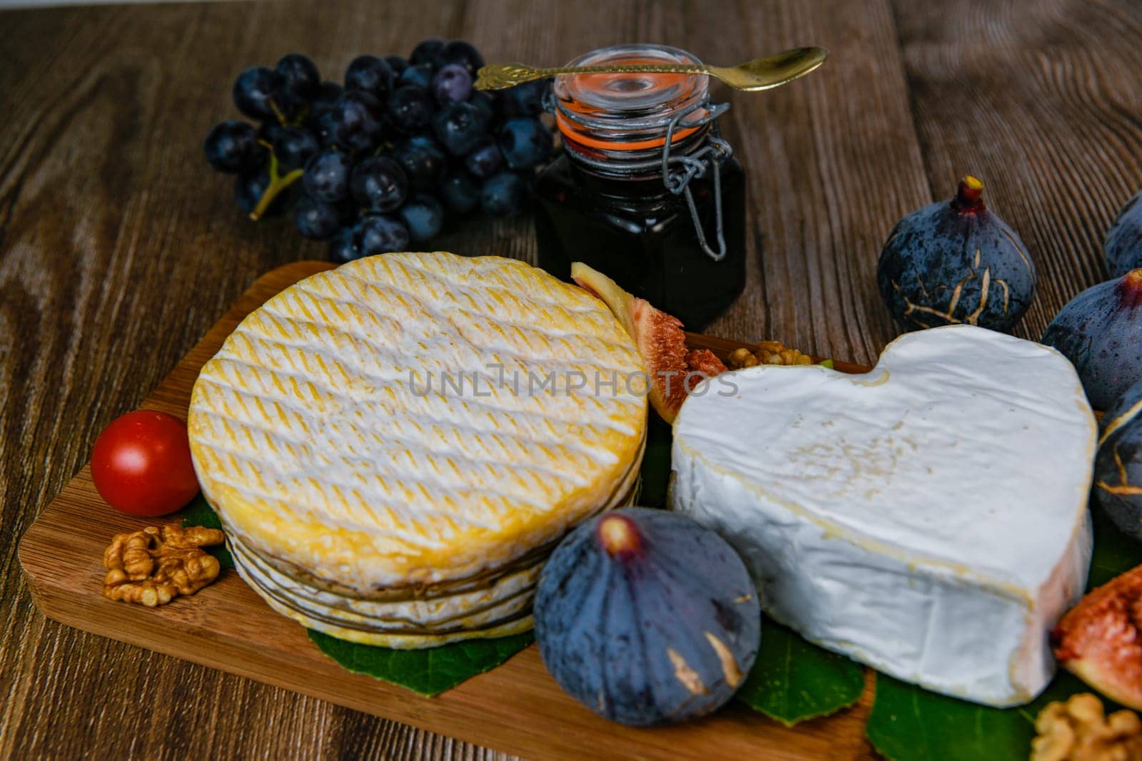 Selection of French cheeses from Normandy, AOP, Livarot, Neufchatel, Pont l'eveque, Rye bread, figs, walnuts, grapes, elderberry gelee. High quality photo