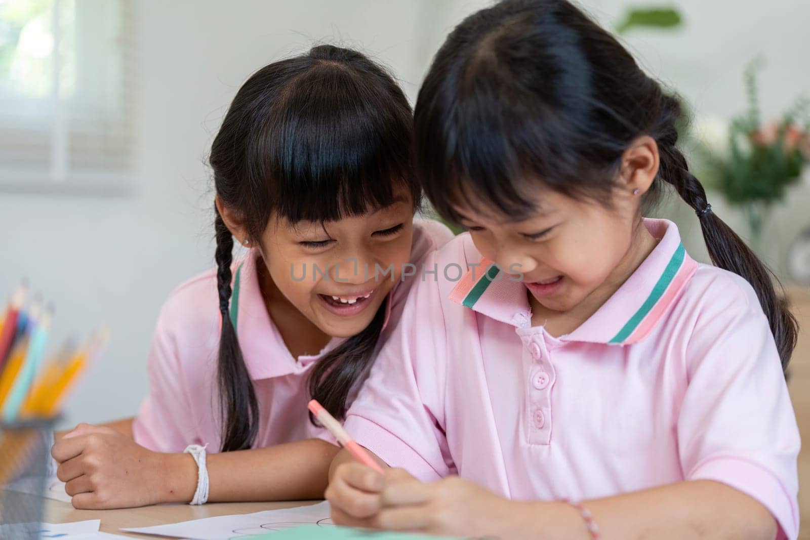 Two friends share a light-hearted moment as they color together, fostering creativity and joy in their school environment.
