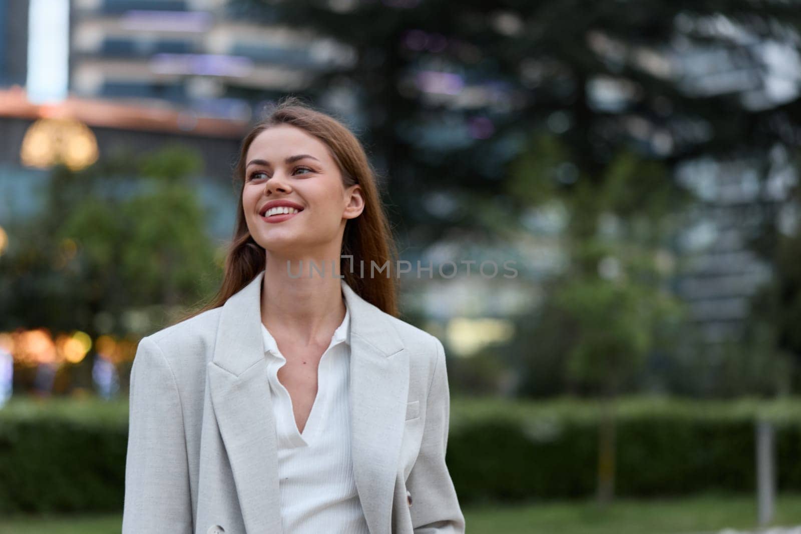 A joyful businesswoman dressed in a sophisticated blazer stands confidently outdoors, radiating positivity and professionalism against an urban backdrop, ideal for corporate themes.