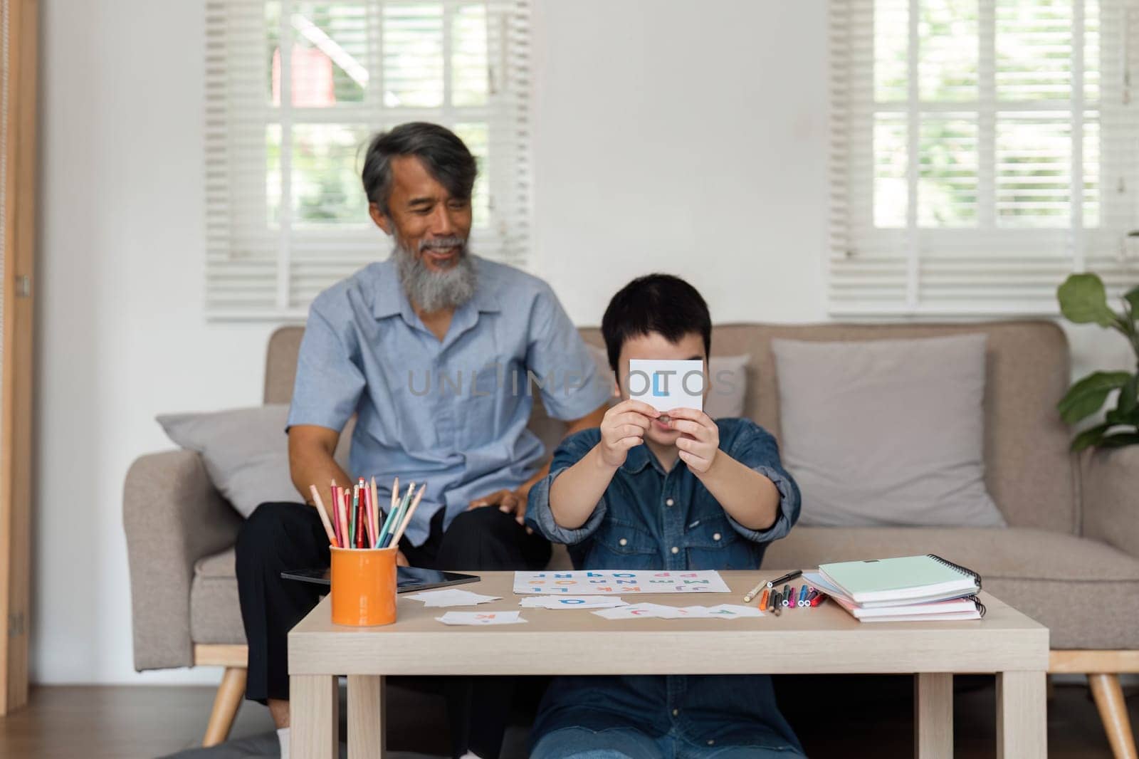 During a cozy home session, a grandfather assists his grandson in recognizing letters, creating a supportive learning atmosphere filled with love and encouragement.