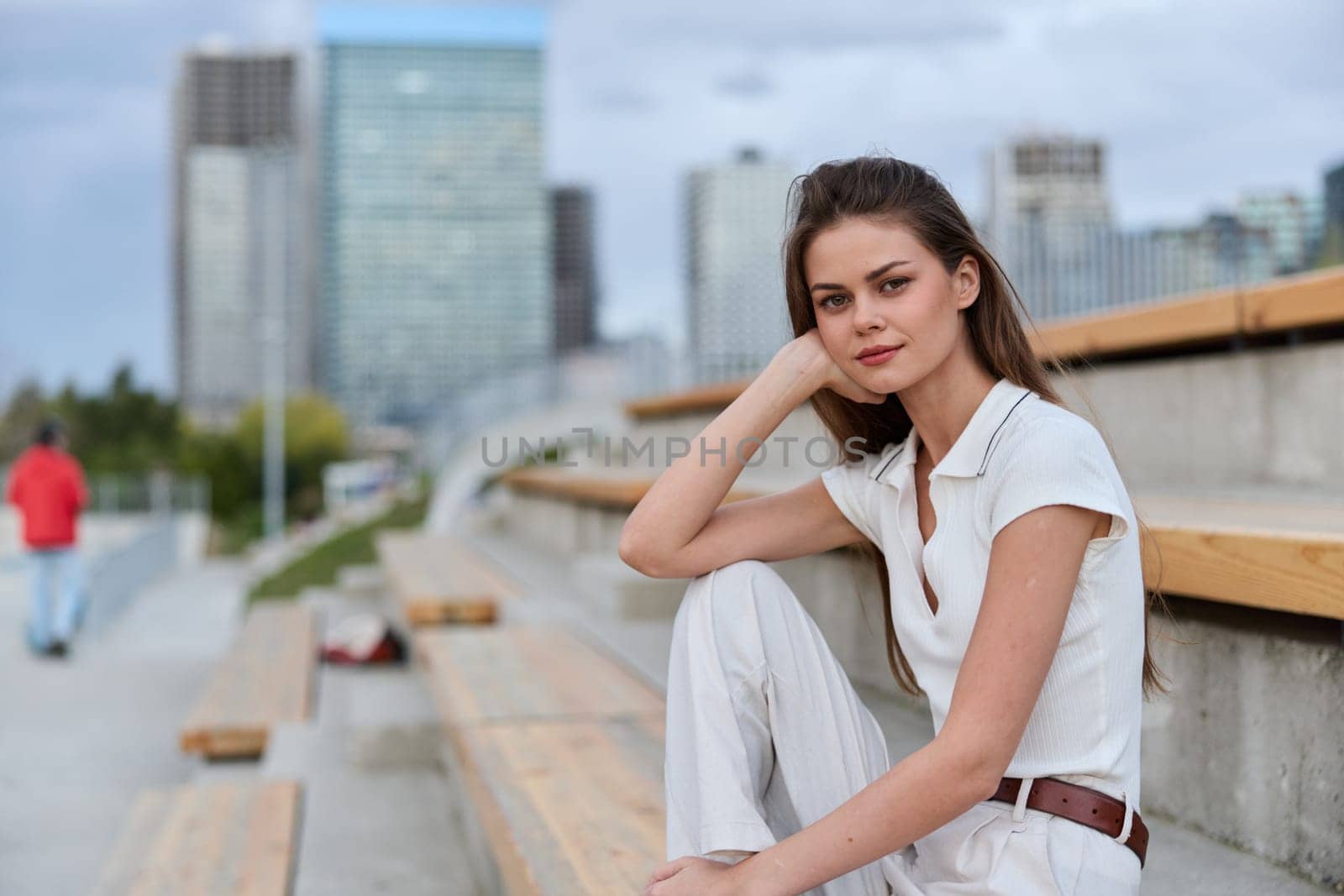 A confident business woman in light clothing sits thoughtfully on a bench, surrounded by an urban backdrop, reflecting a modern and professional vibe perfect for business themes.