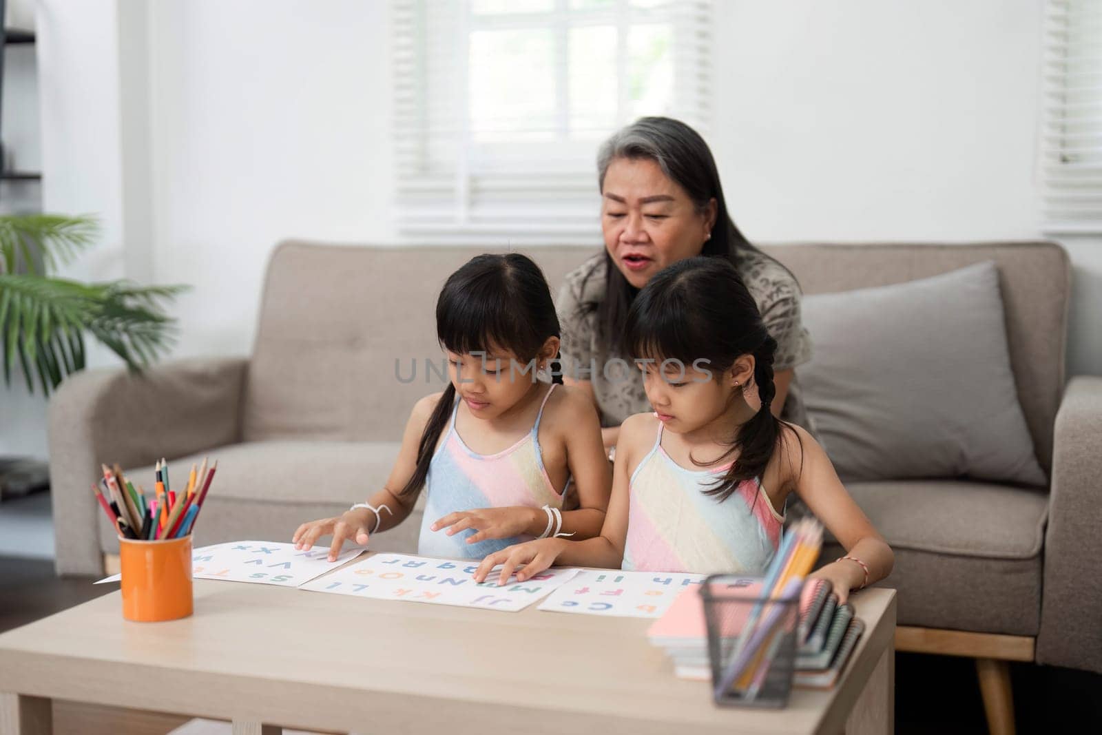 A loving grandmother engages her granddaughters in fun educational activities, fostering a joyful learning environment as they prepare for school.