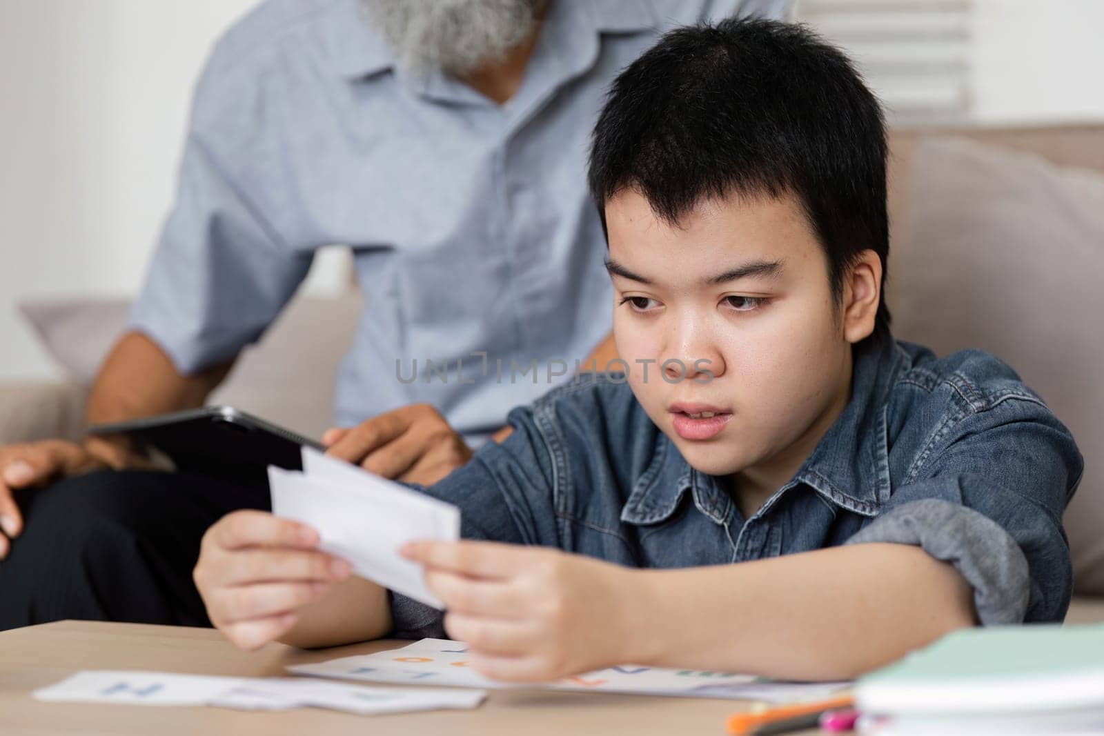 A focused scene where a grandson analyzes educational materials with his grandfather's guidance, highlighting the importance of family support in learning.
