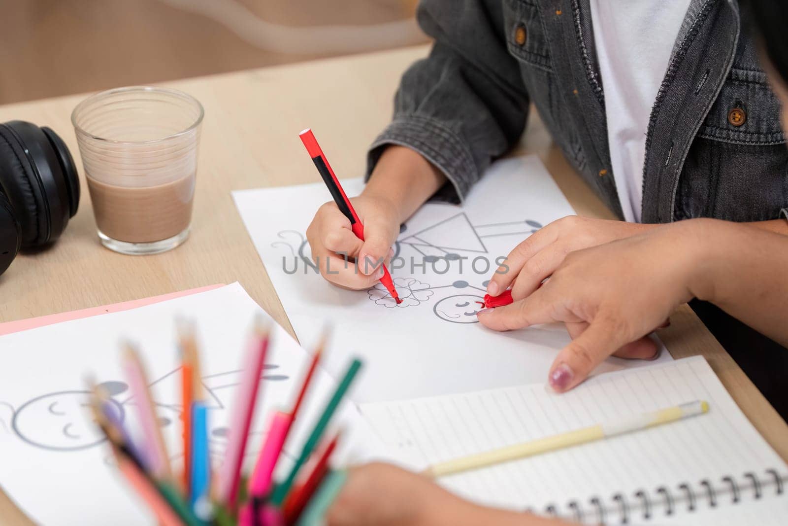 A young artist engages in drawing, using colorful pencils to create imaginative artwork. This moment captures the essence of creativity and learning in a fun environment.