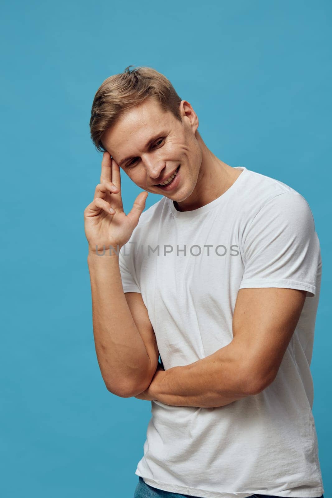 smiling young man wearing white t-shirt standing against blue background with positive emotion, casual style, demonstrating mental health and gadgets awareness. Modern lifestyle concept with focus on mindfulness and digital wellness.