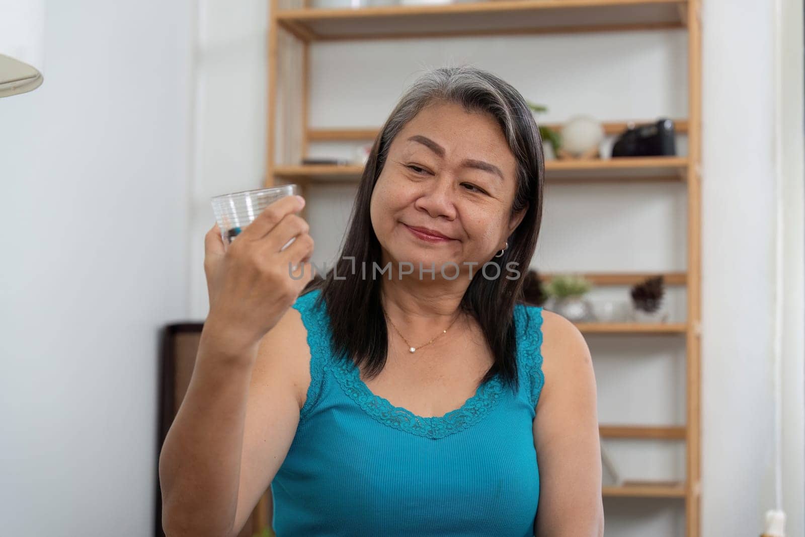 An elderly woman admires a skincare jar in her hand, contemplating her beauty regimen and the importance of self-care in her life.