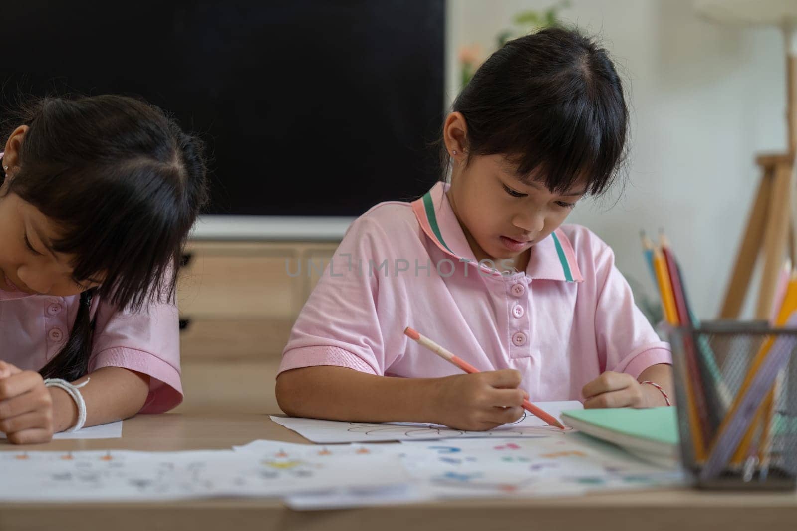 Two sisters concentrate on their coloring tasks, showcasing their creativity and focus. This moment highlights the joy of learning through artistic activities.