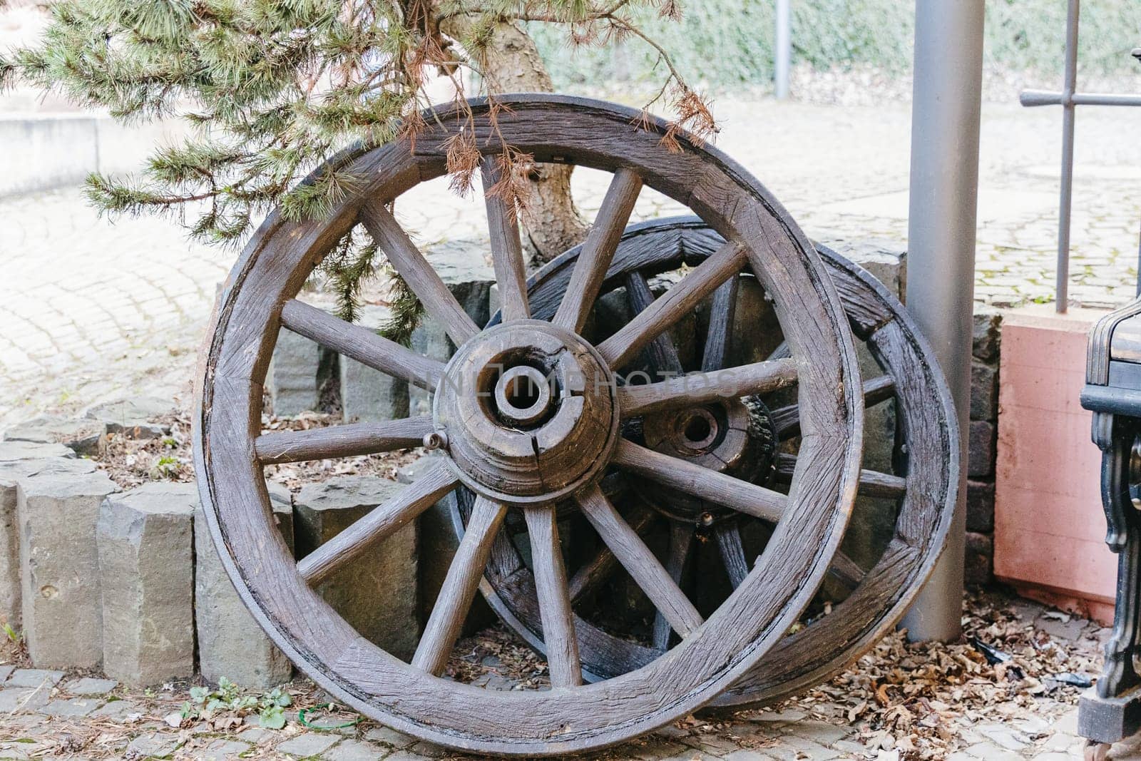 Beautiful view of two old wooden wheels with metal rim from a cart, which stands outside the historical museum in an old castle on a spring day, side view close-up. Concept of historical landmarks, time of travel and tourism.