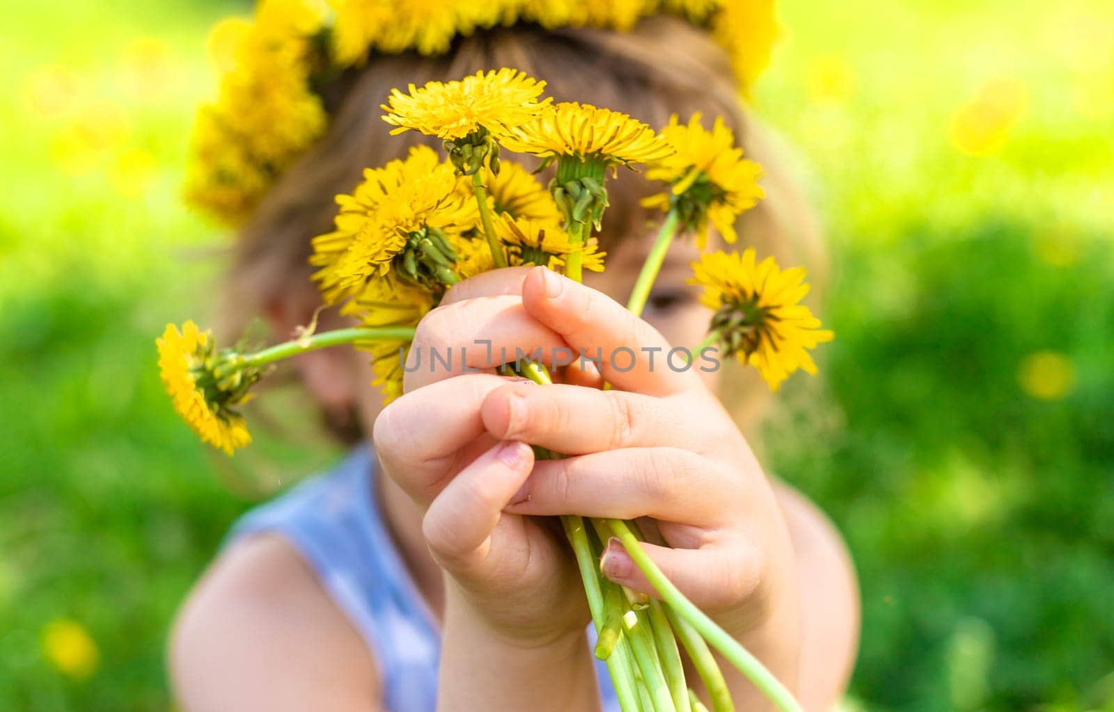 Child in the garden with a bouquet of dandelions. Selective focus. Kid.
