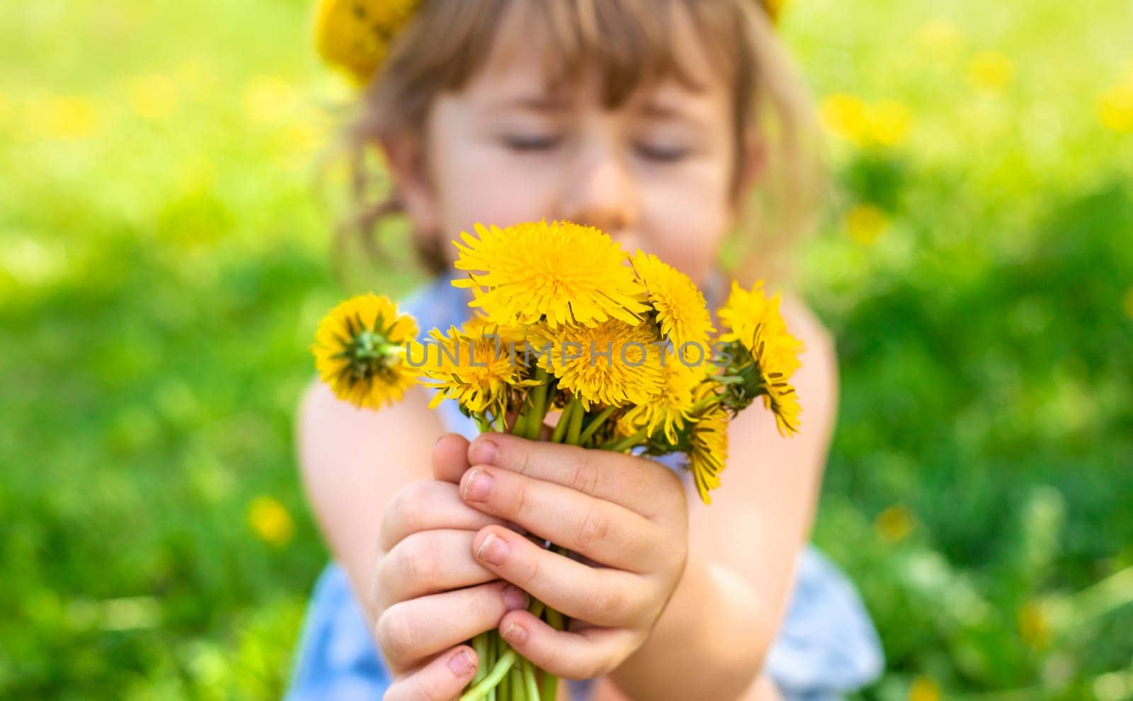 Child in the garden with a bouquet of dandelions. Selective focus. Kid.