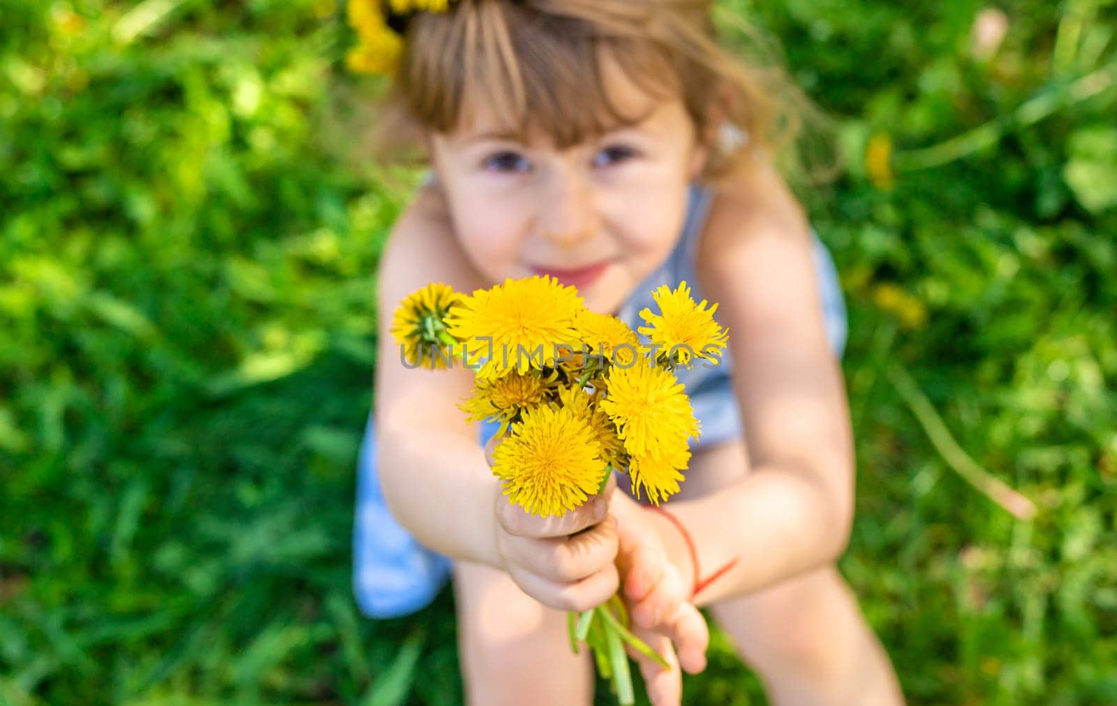 Child in the garden with a bouquet of dandelions. Selective focus. Kid.