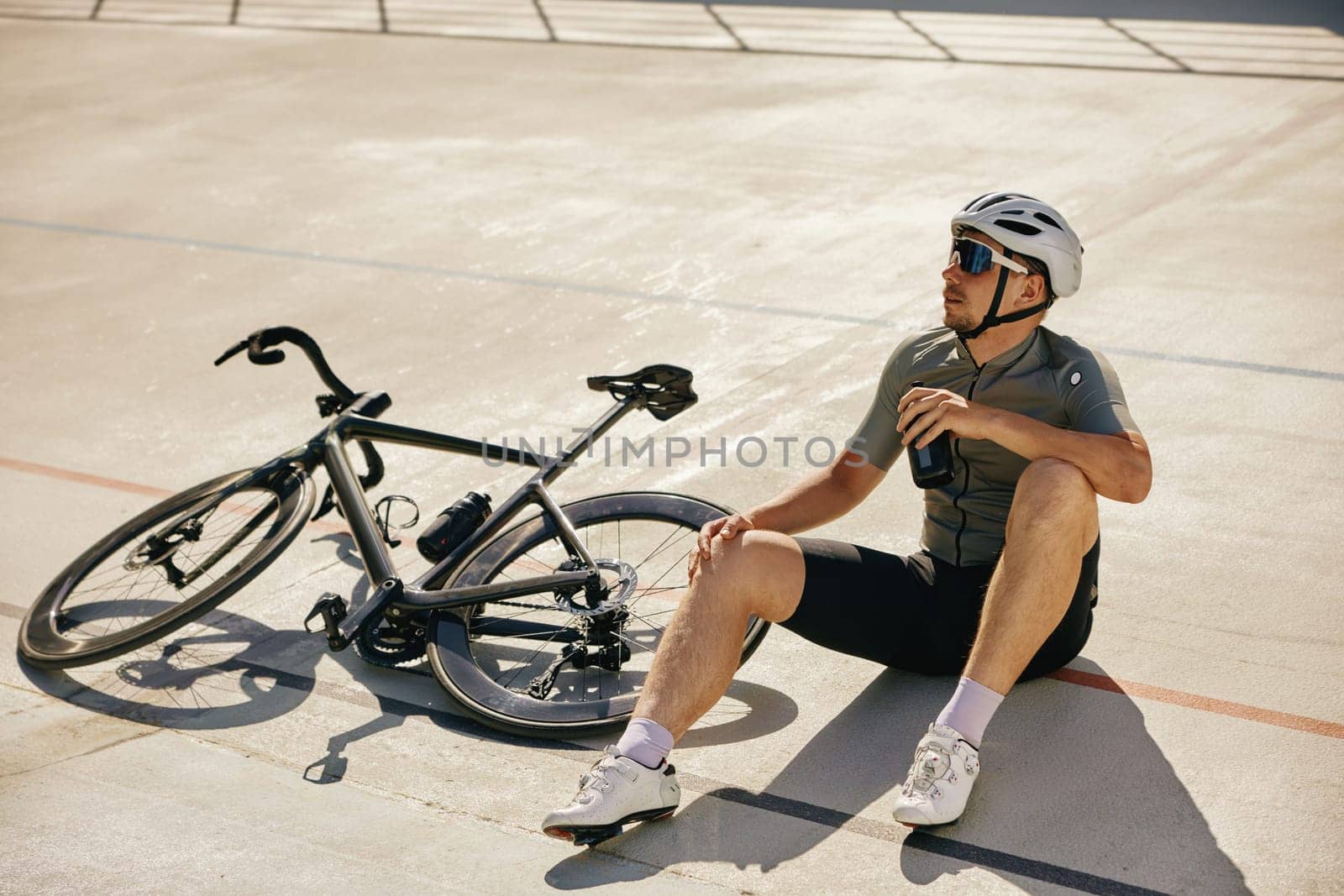 Sportsman with water bottle resting enjoying refreshing time during cycling training on open road sprint track