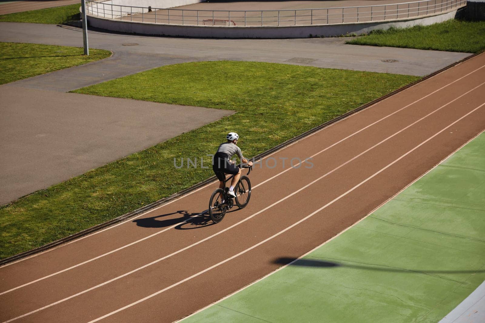 Bicyclist wearing sportive clothing enjoying training cycling on open velodrome track view from afar. Professional sport and hobby recreation concept