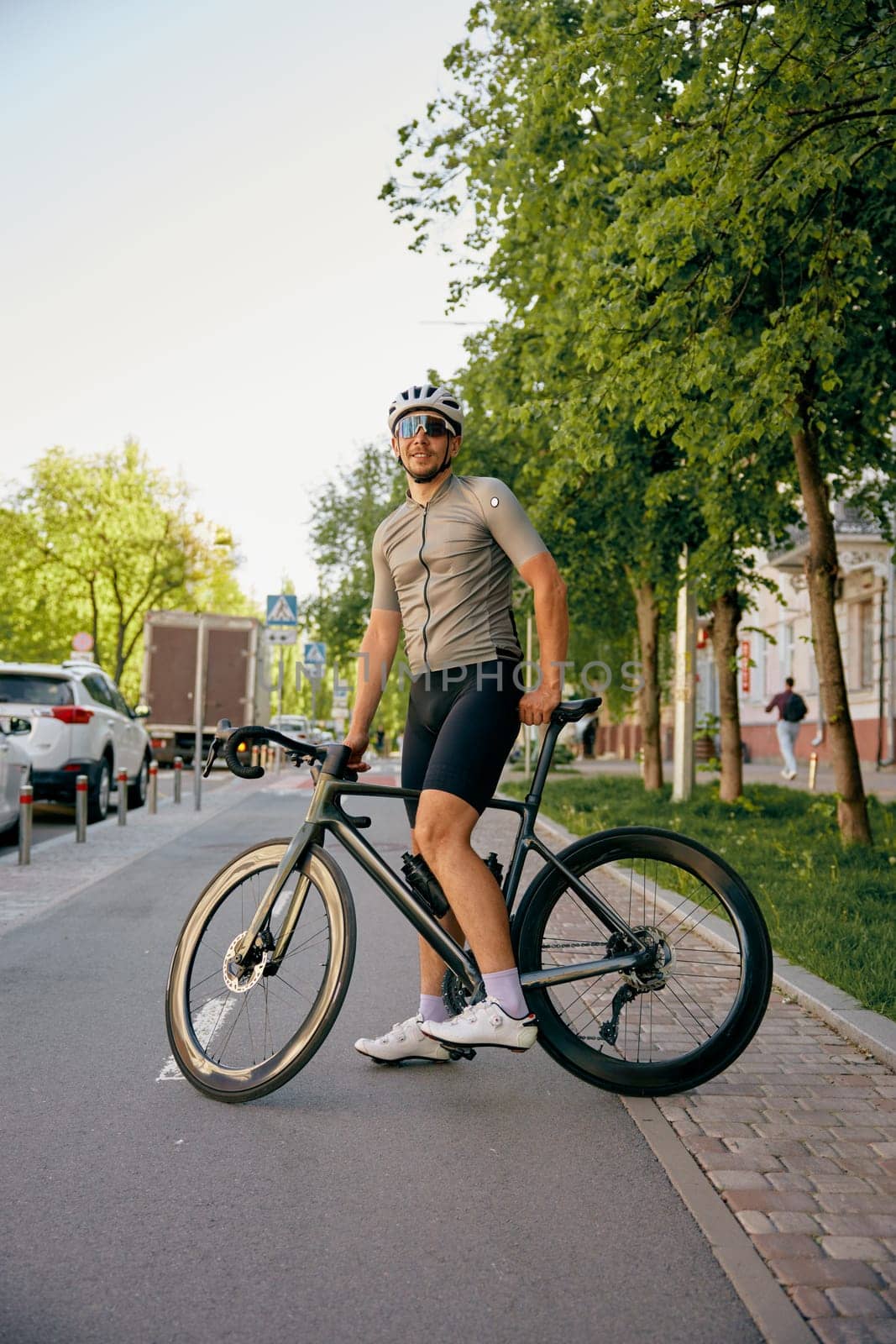 Man bicyclist wearing sportswear riding bike crossing road of urban street. Healthy sporty lifestyle