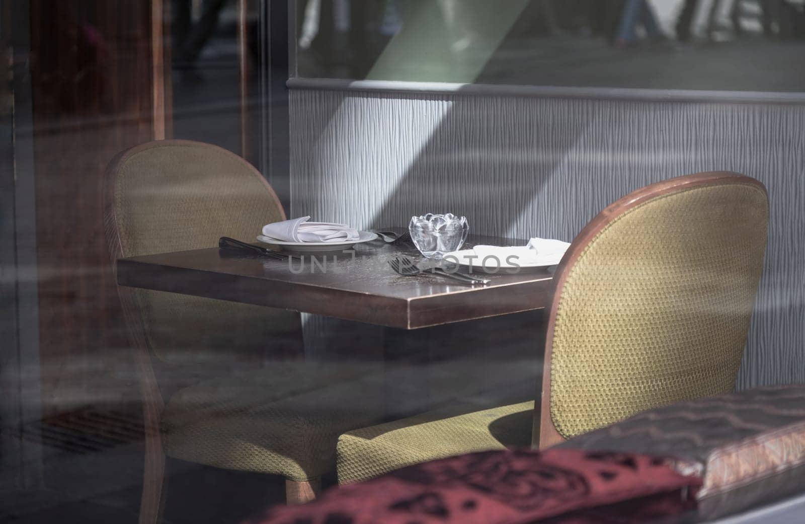 Newcastle, UK - Apr 13, 2025 - Looking through the glass into the Dining table and chairs inside an older vintage restaurant with sunlight shining through in Newcastle upon Tyne, use it as your Wallpaper, Poster and Copy space, Selective focus.