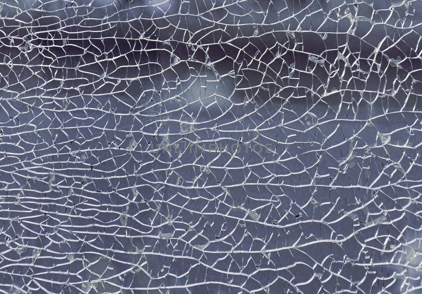 Newcastle, UK - Apr 11, 2025 - Detail of broken tempered glass pane too many small irregular shape pieces holding together. Texture of cracked broken glass cracked by impact, Cracks on the glass surface background, use it as your Wallpaper, Poster and Copy space, Selective focus.