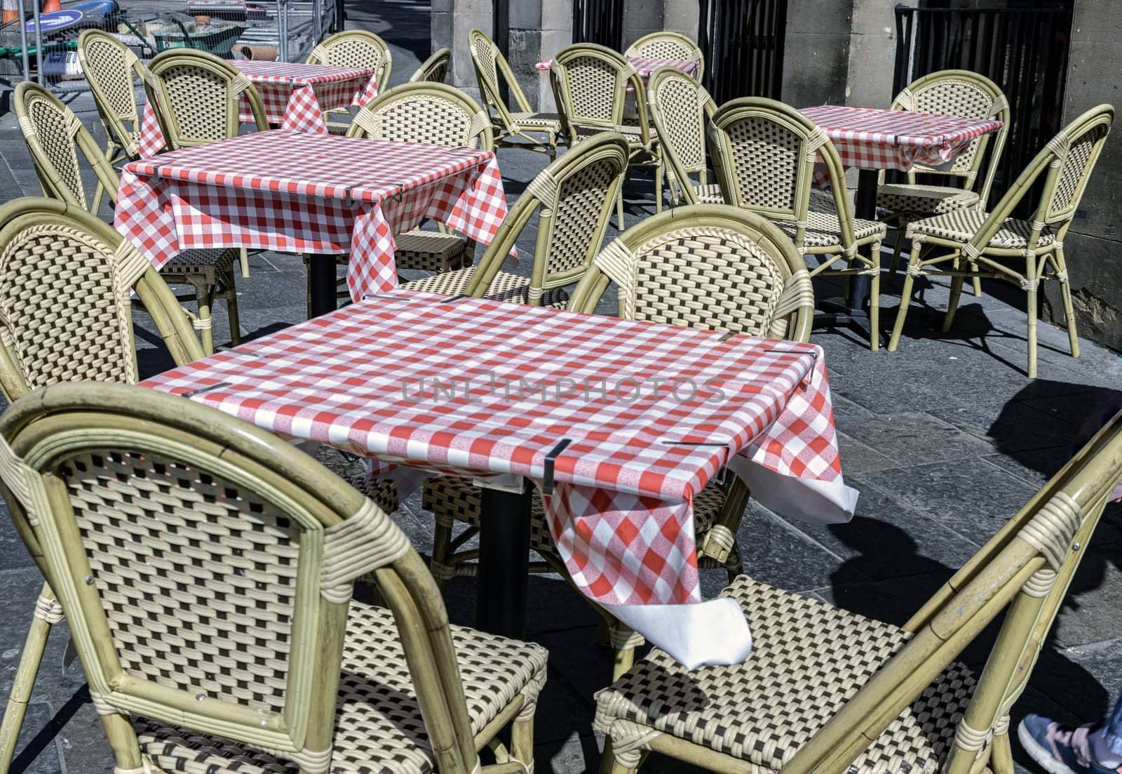 Newcastle, UK - Apr 13, 2025 - Empty tables and chairs covered red and white checkered tablecloths with chairs outside a cafe on street. Outdoor summer cafe in the afternoon, use it as your Wallpaper, Poster and Space for text, Selective focus.