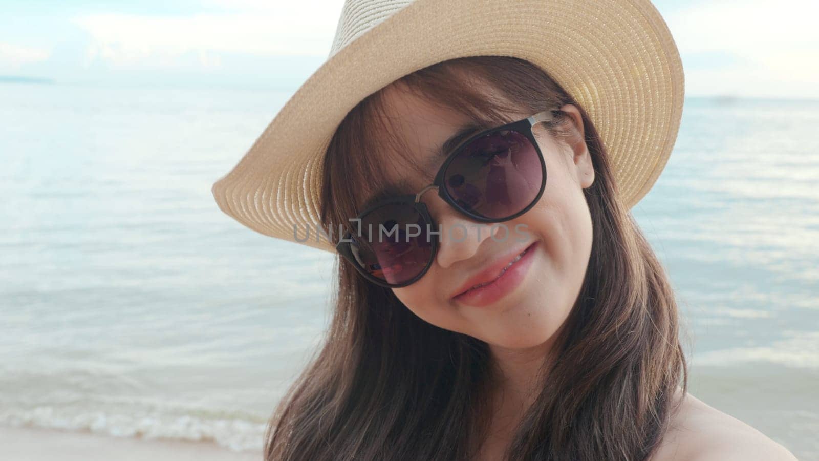 Beautiful Asian woman wear sunglass and hat selfie taking vacation selfie portrait at tropical paradise beach, Happy female in bikini swimsuit having fun video call to friend, Summer holiday