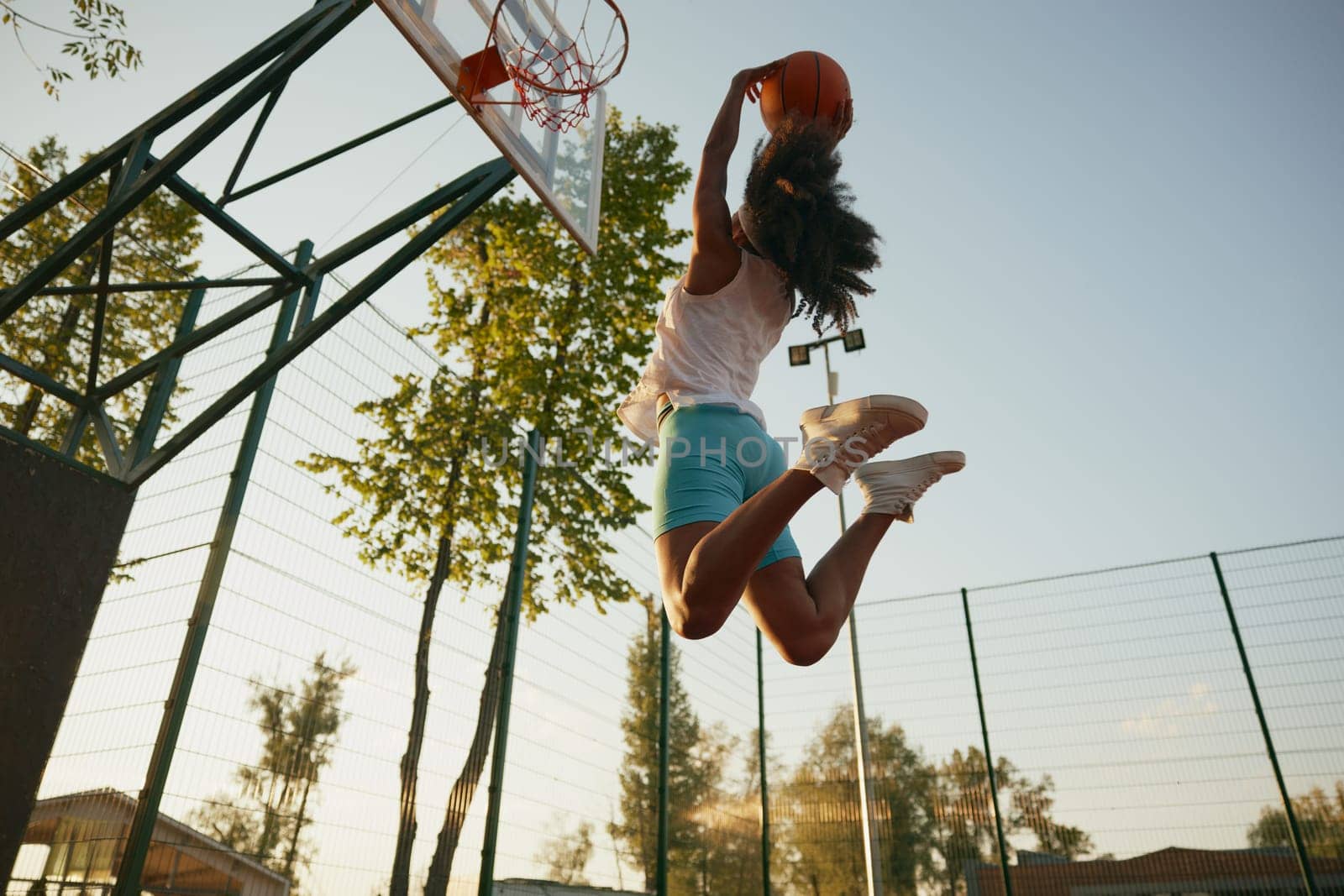 Young woman basketball player frozen in motion jumping high making slam dunk. Concentration and athleticism concept