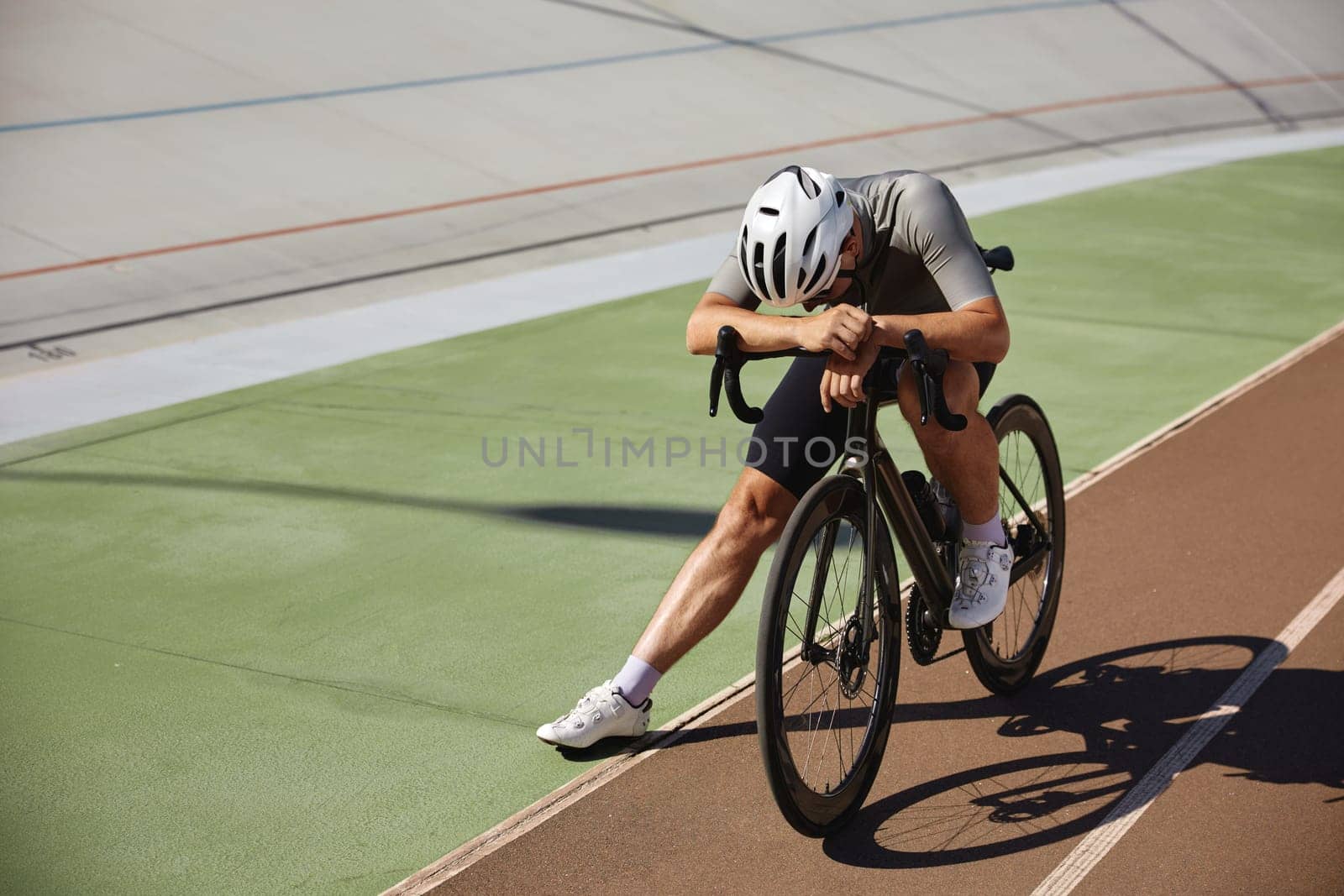 Tired exhausted bicyclist athlete stopped on sprint track after hard cycling training. Professional sport and hobby recreation pursuit concept