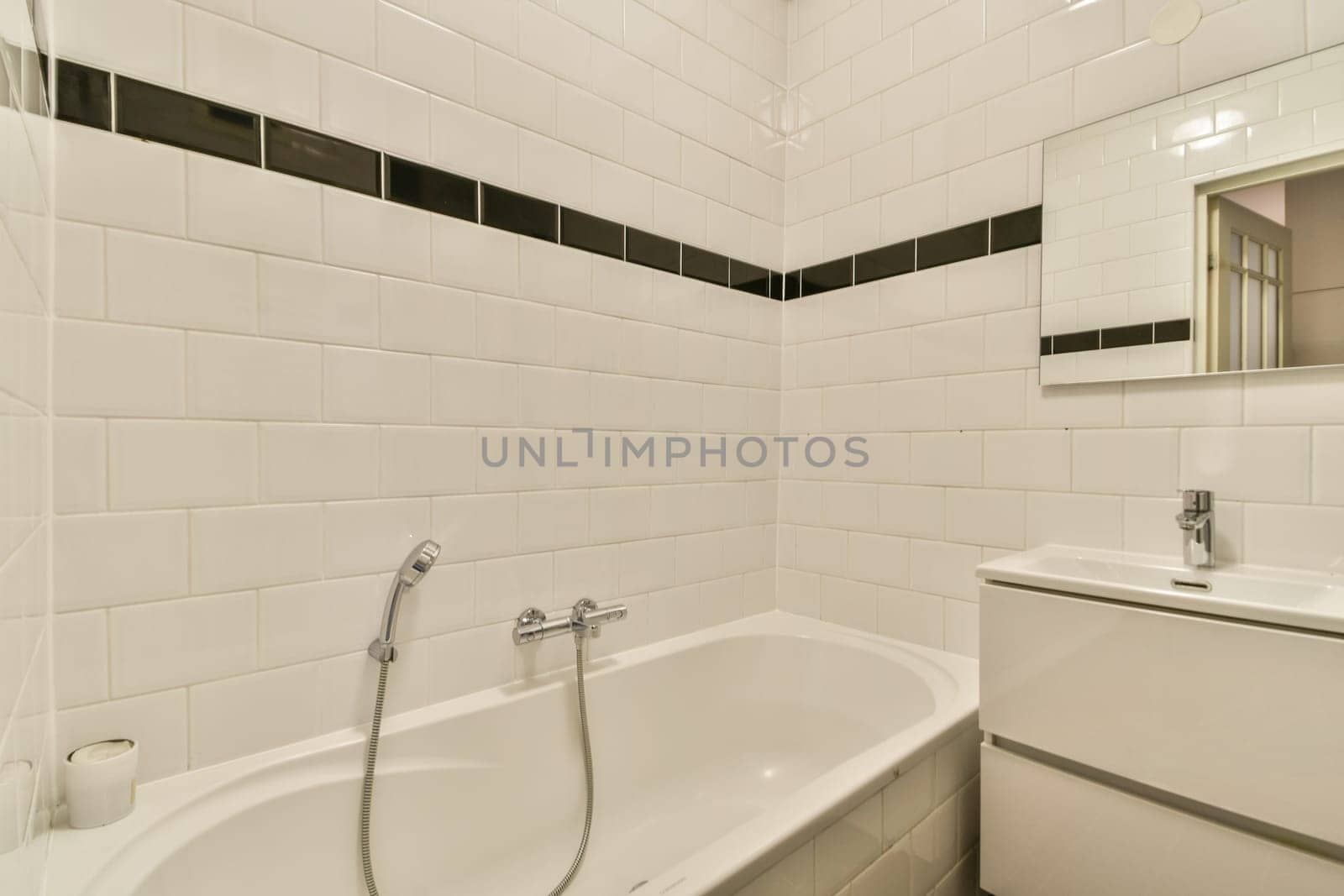 A sleek and contemporary bathroom showcasing a white bathtub, stylish fixtures, and minimalistic design with black accents on tiles.