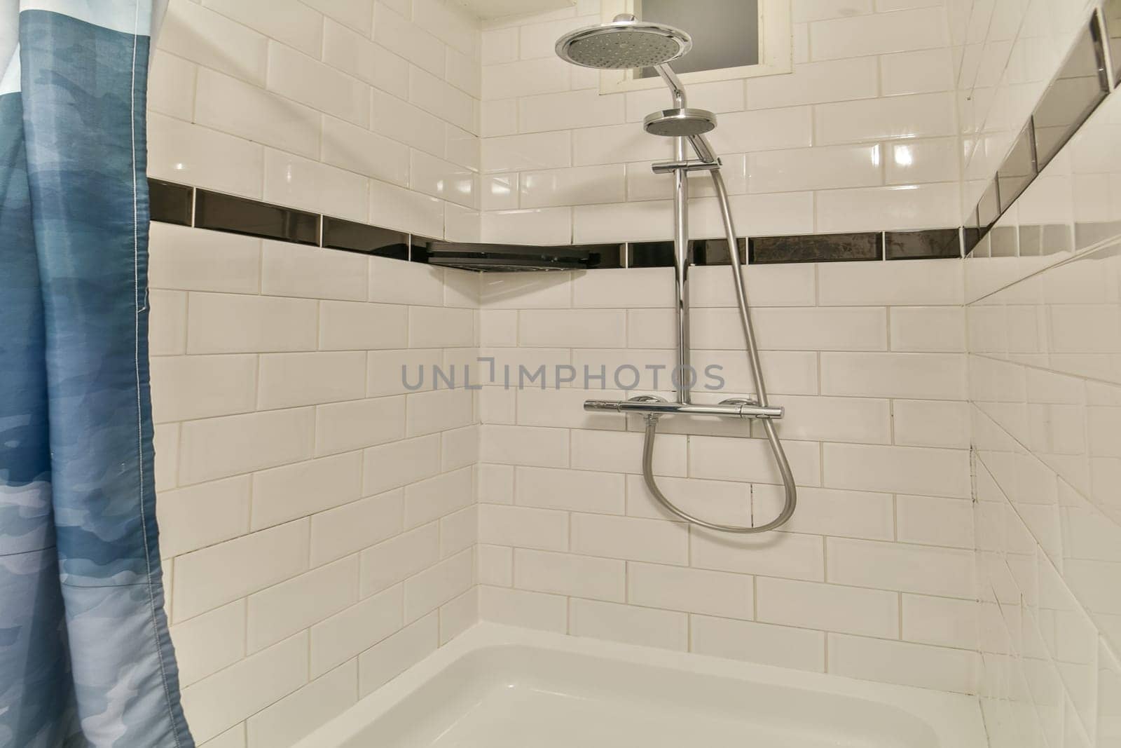 A contemporary shower area showcasing white tiled walls, a stylish showerhead, and a decorative curtain, reflecting modern design aesthetics.
