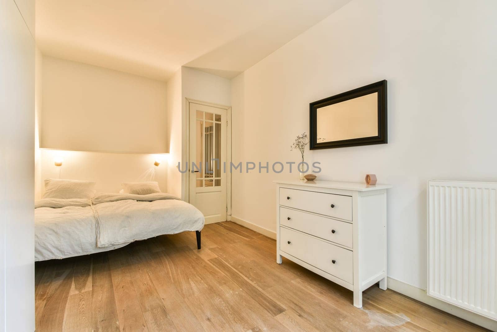 A serene and minimalist bedroom featuring a neatly made bed, a stylish dresser, and warm lighting that creates a tranquil atmosphere.