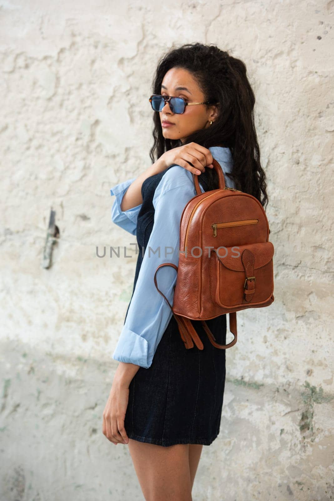 A fashionable model confidently showcasing a modern outfit while sporting a brown backpack accessory