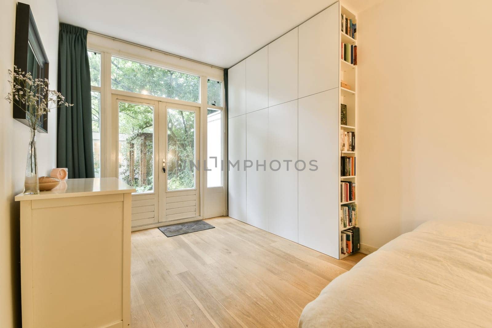 A spacious and bright modern bedroom featuring minimalist decor, natural light through large windows, and soothing wooden flooring, creating a serene atmosphere.