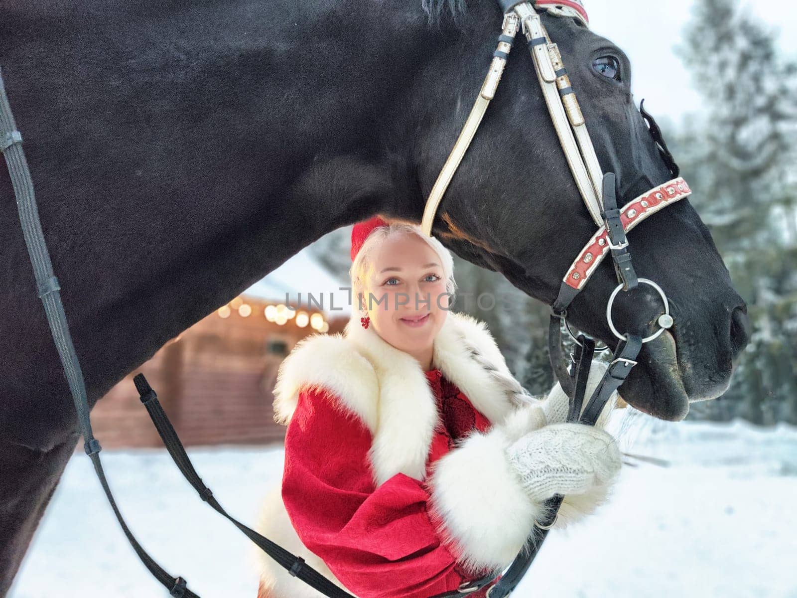 A Russian girl in traditional attire enjoys Maslenitsa festivities with a horse in the winter.