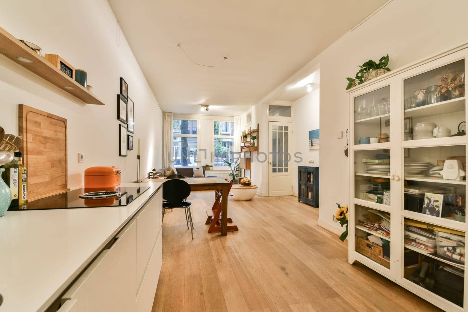 A bright and spacious modern interior featuring wooden flooring, sleek furniture, and large windows that invite natural light, creating an open and inviting atmosphere.
