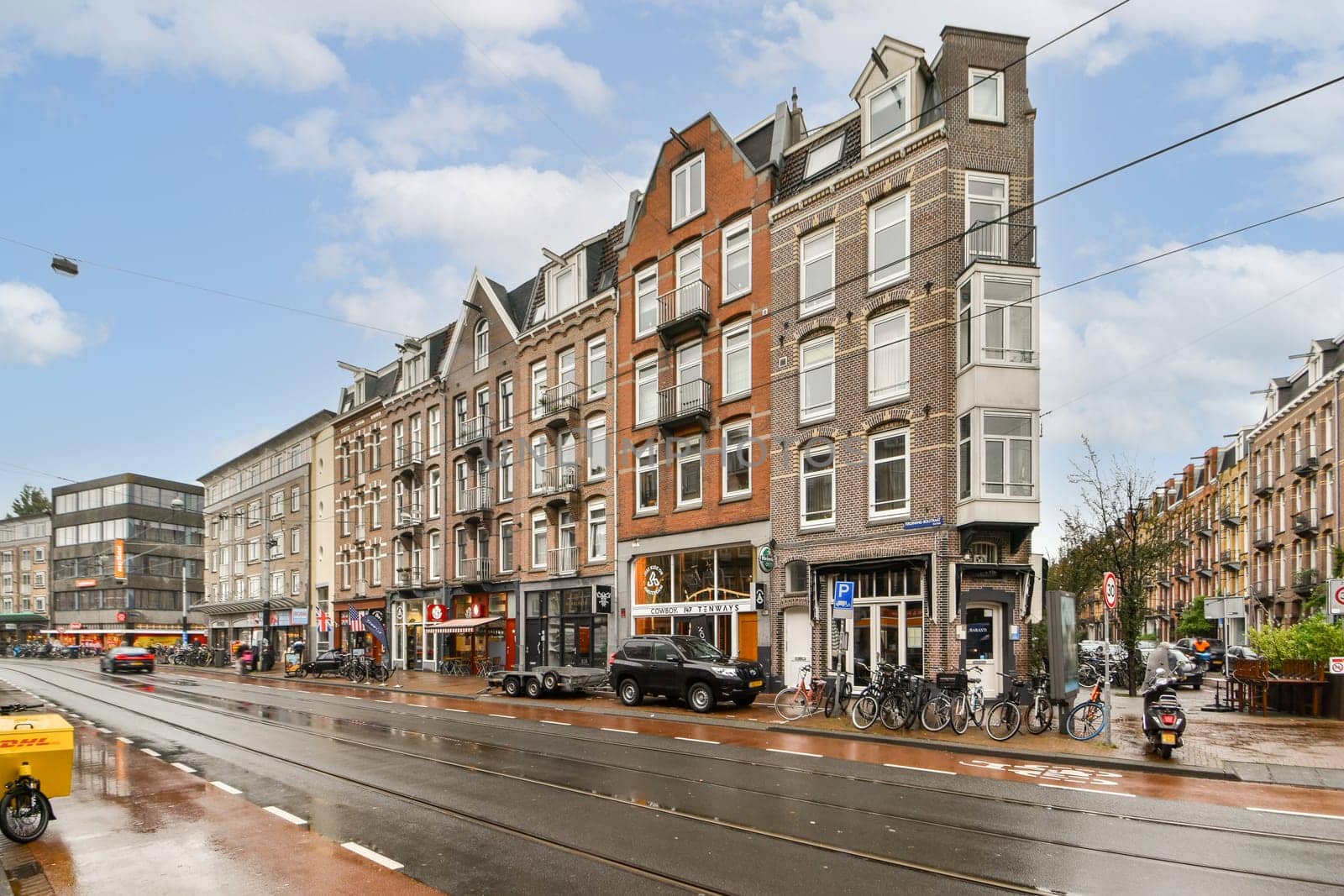 A vibrant streetscape showcasing Amsterdam's distinctive architecture and lively urban atmosphere. Shops and bicycles align with the classic buildings.