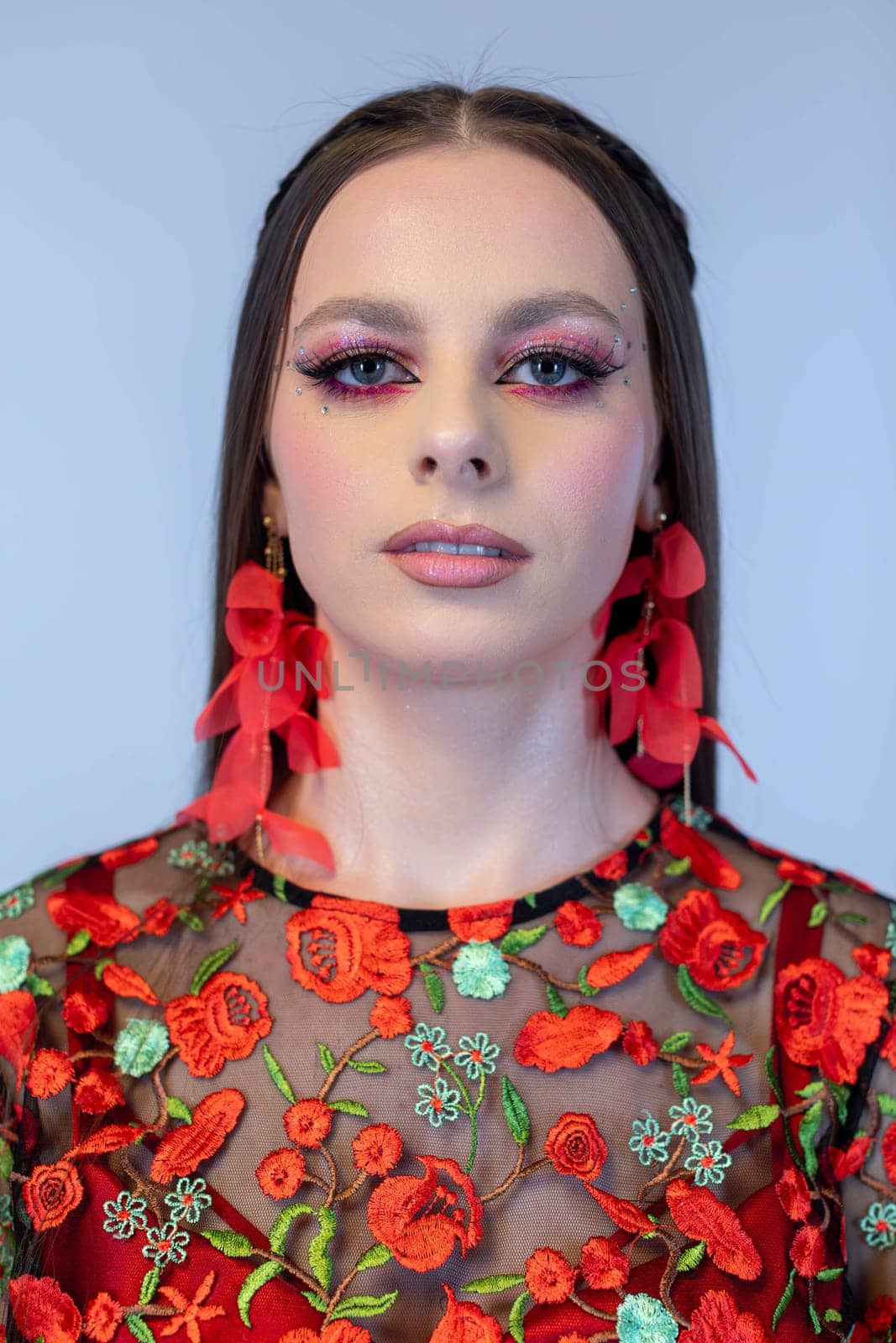 This is a striking fashion portrait that showcases intricate floral embroidery along with bold, vivid makeup