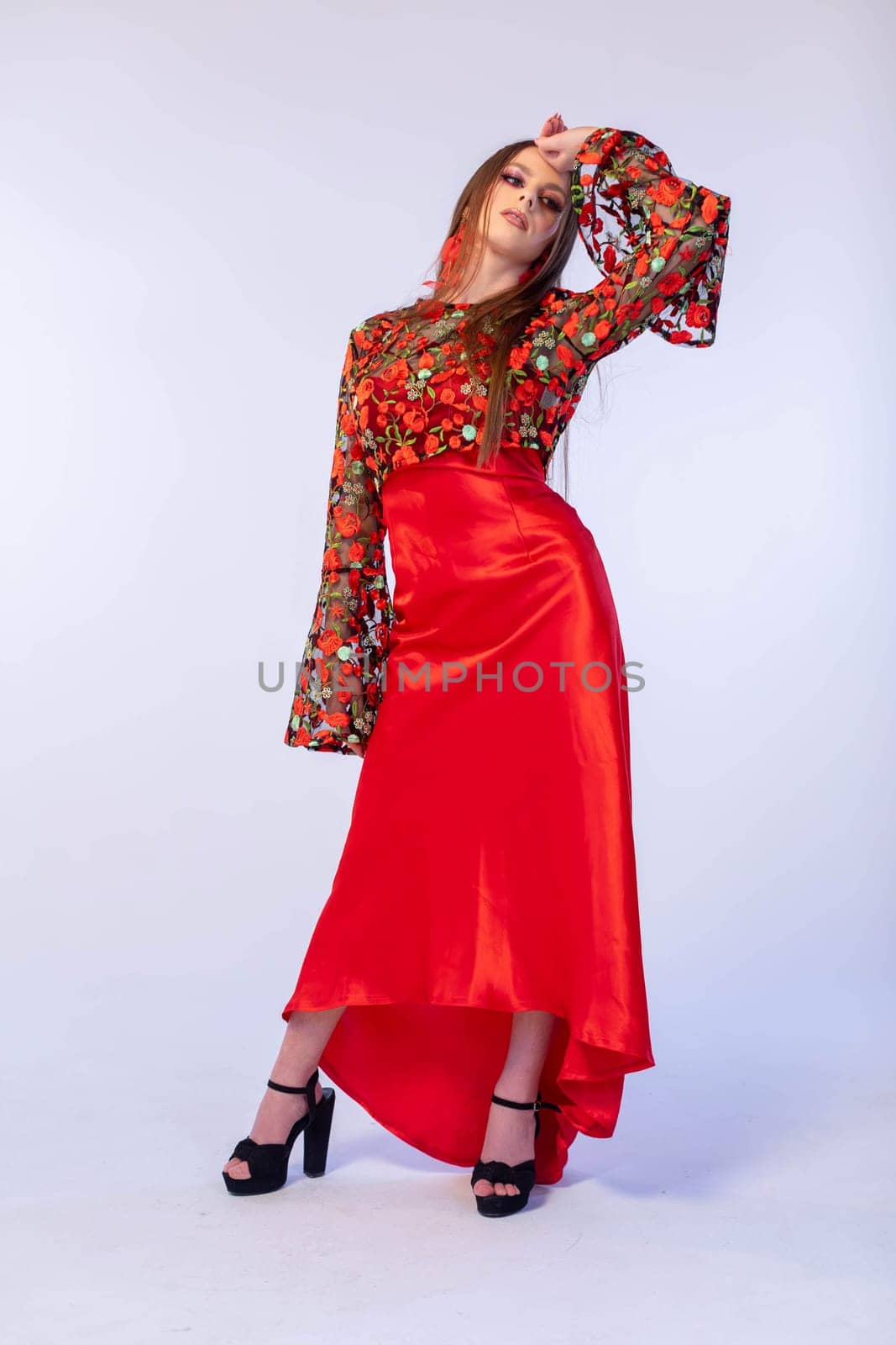 A confident model striking a pose in a vibrant and eyecatching floral top paired with a stunning red satin skirt
