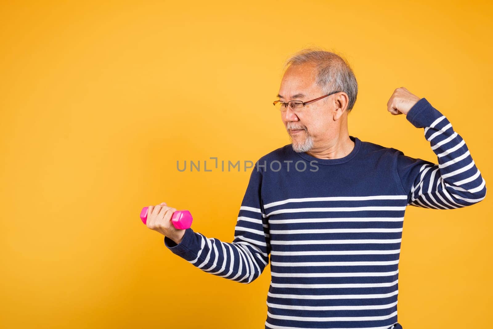 Portrait Asian smiling old man holding a pink dumbbell lifts it with strength and power studio shot isolated yellow background, senior man pensioner, Body care, weight loss lifestyle