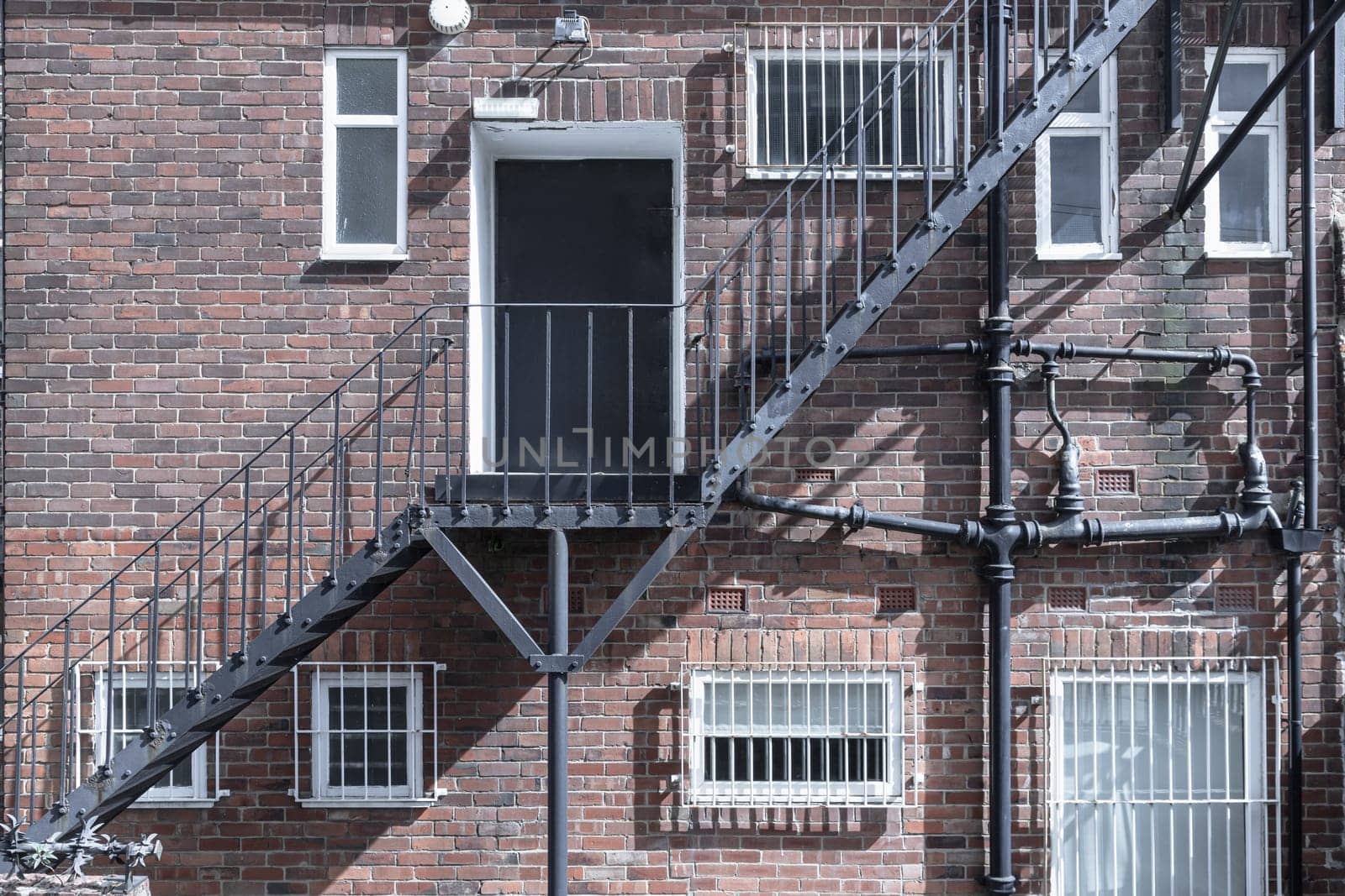 Newcastle, UK - Apr 13, 2025 - External Metal Staircase attached at the rear of old brick building in Newcastle. Urban architecture and emergency exit design, the metal rugged construction, perfectly integrated into the architectural of the building with a brick, use it as your Wallpaper, Poster and Space for text, Selective focus.