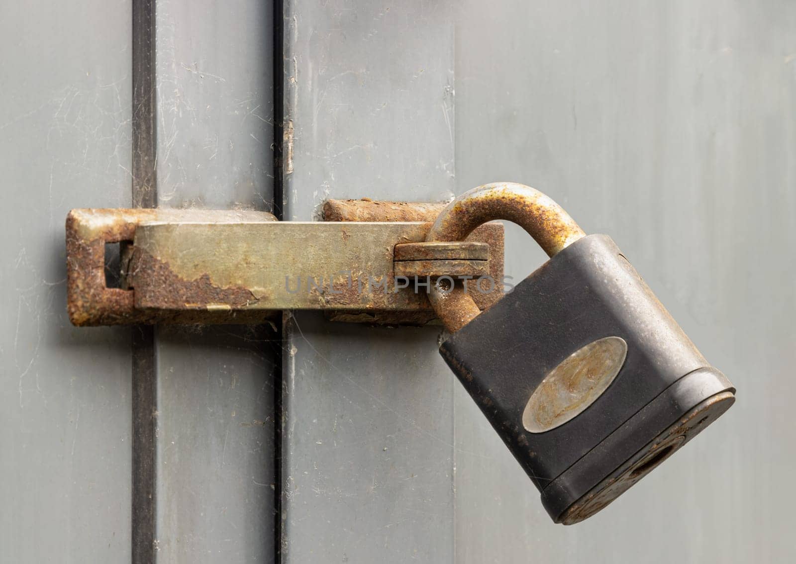 Newcastle, UK - Apr 13, 2025 - Metal locked padlock in Rusty iron door lock hasp latch on the Wooden door frame. Storage security, use it as your Wallpaper, Poster and Space for text, Selective focus.