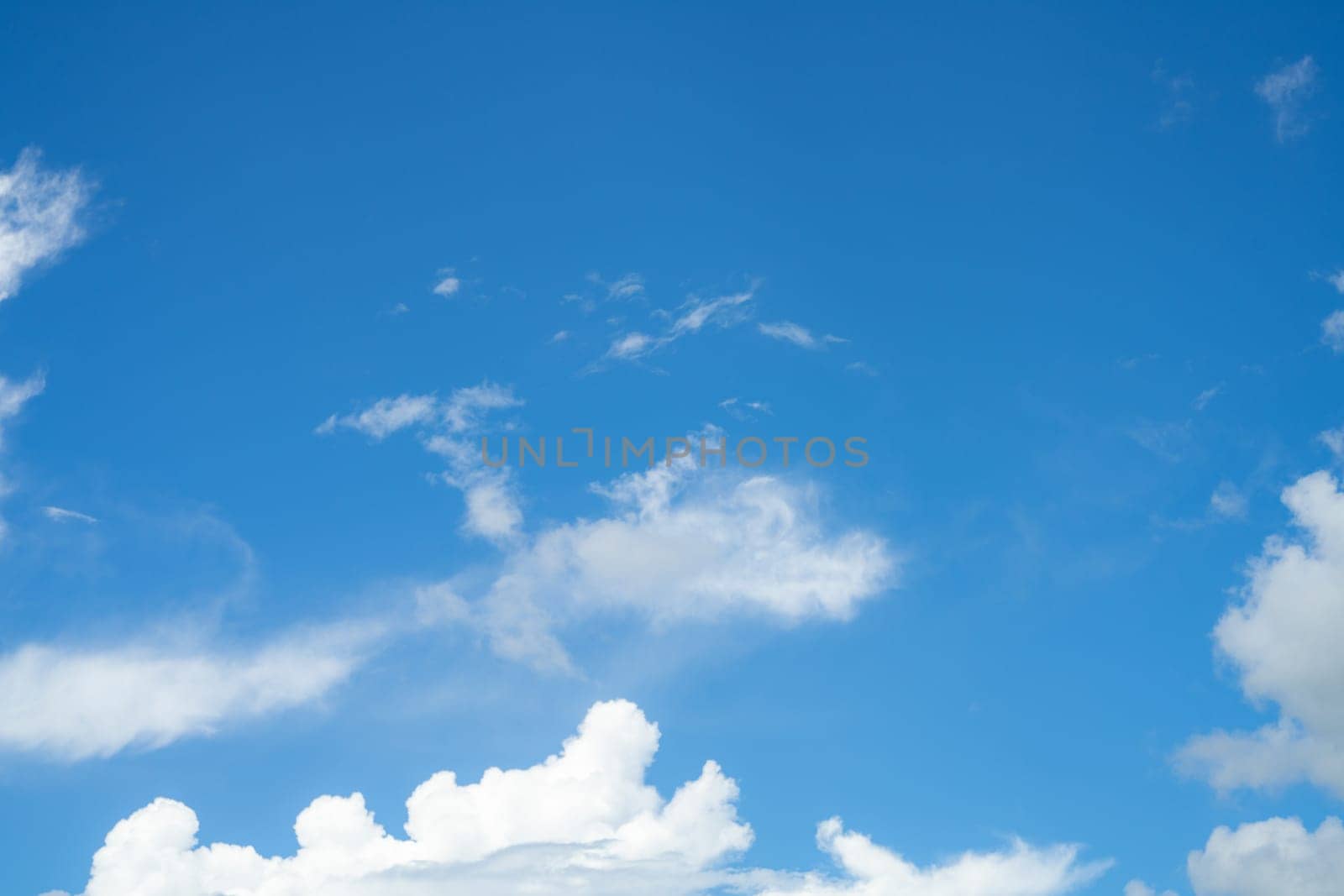 Blue sky with fluffy white cumulus clouds on bright sunny day, natural cloudscape background for environment and weather concepts. Summer day. Ozone awareness, clean air, environmental protection.