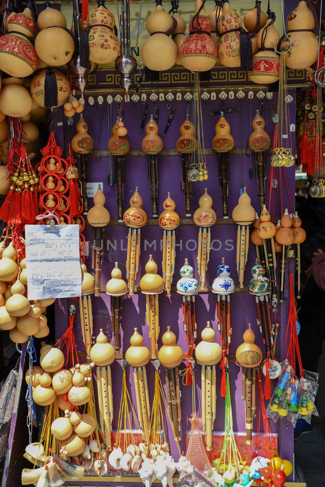Shanghai, China - 2 April 2025: Colorful display of traditional Chinese hulusi wind instruments and souvenir gourds at a Yunnan Old Street market stall, featuring hand-painted dragon designs and red tassels