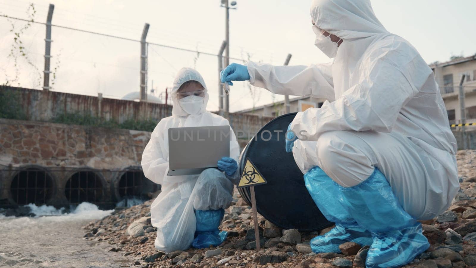 Ecologist sample water from the river and get fishes dead to check effected case in laboratory, Biologist wear protect suit and mask collects sample of waste water from industrial, problem environment