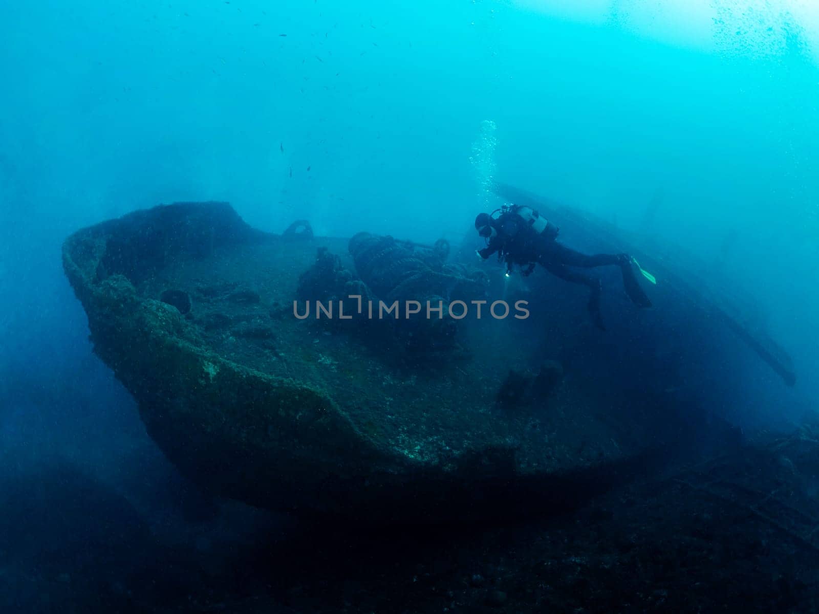 unrecognizable scuba diver diving into the blue ocean near of a wreck, concept of underwater adventure and active leisure lifestyle, copyspace for text
