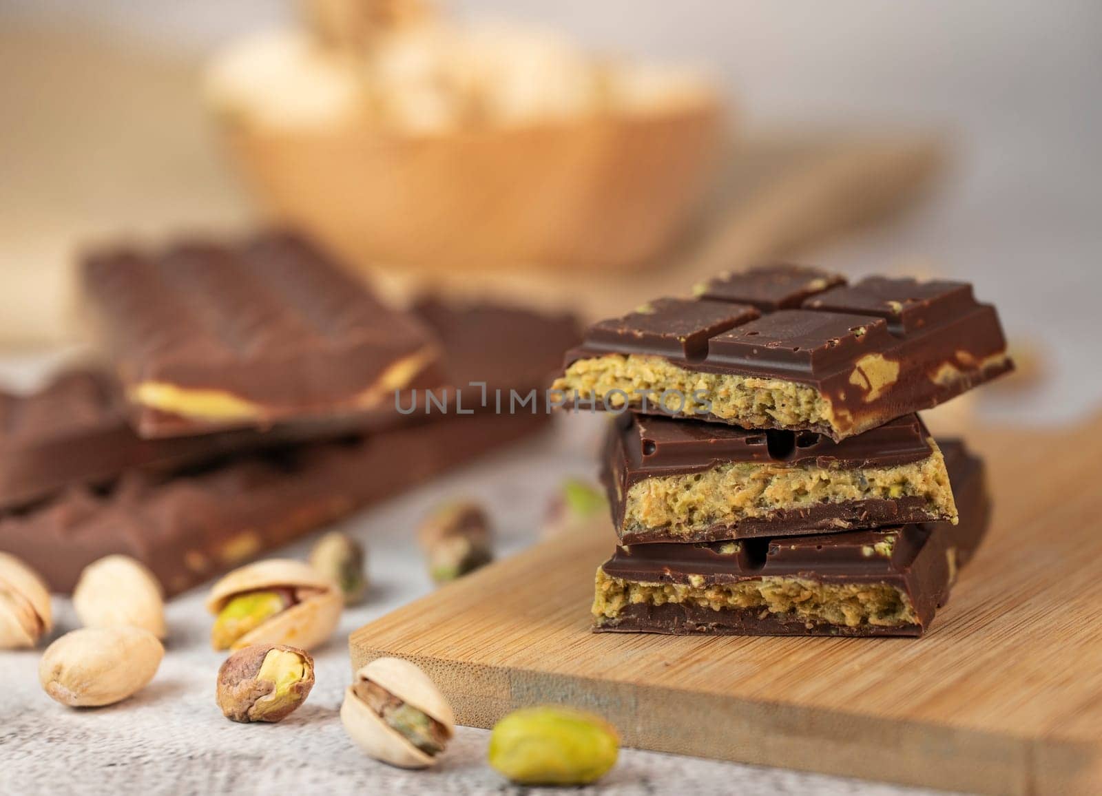 Gourmet chocolate mixed with crunchy kadaif pistachio pieces is beautifully presented on a wooden board, making a perfect treat in Dubai's culinary scene.